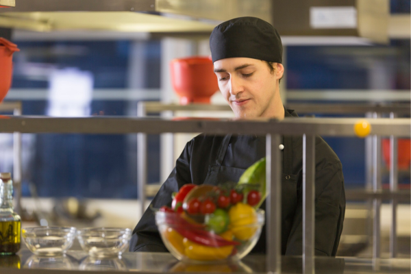 Technicien PN Line réalisant un nettoyage en profondeur d’une cuisine professionnelle à Paris avec équipement de protection et produits écologiques.